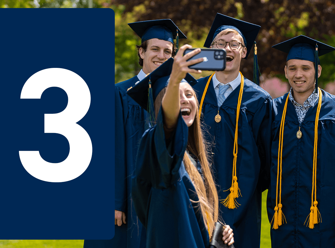 Graduates in cap and gown taking a selfie.