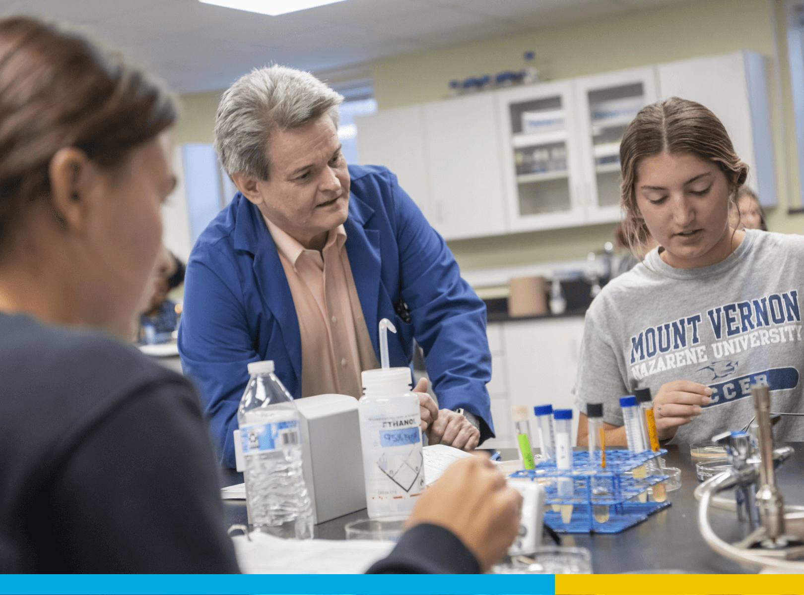 A professor working closely with students testing samples