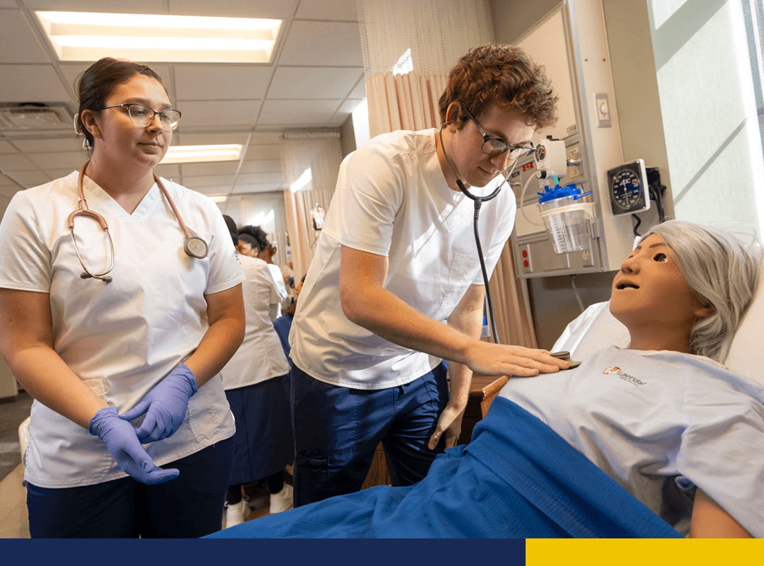 Two healthcare students working with a mannequin